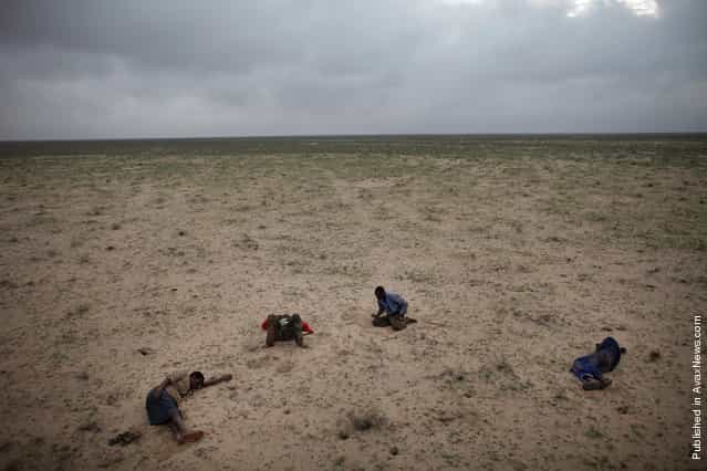 In this photo released by Word Press Photo, the 1st Prize Contemporary Issues Stories by Ed Ou, Canada, Reportage by Getty Images, shows four Somali refugees en route to Yemen sleep in the desert after traveling all night on muddy roads and in pouring rain, Somaliland, March 15, 2010
