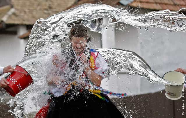 A woman runs as men throw water at her as part of traditional Easter celebrations in Holloko, Hungary, 100 km (62 miles) east of Budapest, on April 14, 2011. Locals from the World Heritage village of Holloko celebrate Easter with this traditional [watering of the girls], a tribal fertility ritual rooted in the area's pre-Christian past