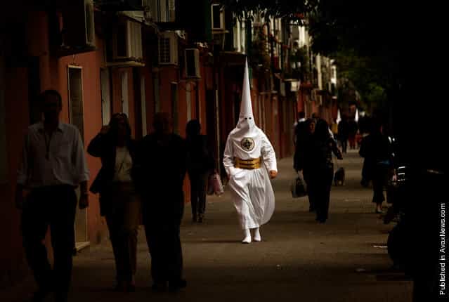 A penitent from the San Gonzalo brotherhood walks toward a church to take part in a procession in Seville, Spain