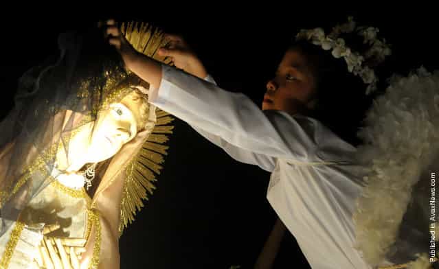 A child dressed as an angel lifts the veil over a statue of Mother Mary during an Easter mass outside St. Domingo Church in Quezon City, east of Manila, Philippines, on April 24, 2011. The traditional Salubong mass reenacts the meeting of the Risen Christ and the sorrowful Mother Mary on the dawn of Easter Sunday