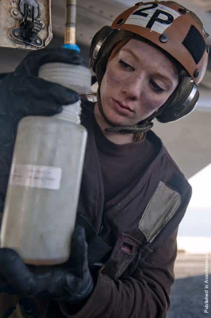 Aviation Ordnanceman Airman Samantha Phillips collects fuel samples from an F/A-18E Super Hornet from the Black Aces of Strike Fighter Squadron (VFA) 14 on the flight deck of the Nimitz-class aircraft carrier USS John C. Stennis (CVN 74)