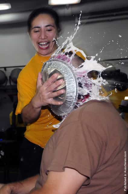 Ensign Patricia Cunanan shoves a pie in the face of Command Master Chief Michael Lucas during a fundraiser aboard the amphibious dock landing ship USS Comstock (LSD 45)