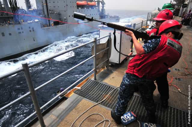 Gunner's Mate Seaman Megan Halliburton fires a shot line from the amphibious assault ship USS Boxer (LHD 4) to the Military Sealift Command dry cargo and ammunition ship USNS Alan Shepard (T-AKE 3) during a replenishment at sea