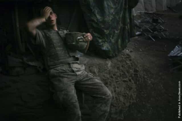 A soldier of Second Platoon, Battle Company of the Second Battalion of the US 503rd Infantry Regiment sinks onto an embankment in the Restrepo bunker at the end of the day