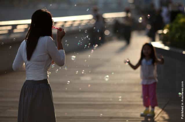 A woman blows bubbles toward a child on a sunny afternoon in Hong Kong on April 9, 2011