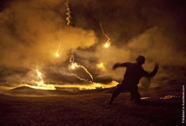 Staff Sgt. Angel Alvarez assigned to the Warrior Training Center at Fort Lee, Va., cocks back to throw a pyrotechnic grenade simulator into the sky during a night fire event for the 2011 Department of the Army Best Warrior Competition. During the event, competitors fired from the prone supported and prone unsupported firing positions while pyrotechnics exploded all around them