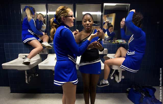 Palo Verde High School cheerleaders Ashley Gray, left and Gigi Tadeo use locker room sinks to give them a boost for applying makeup while sophomore cheerleader Virginia Bemer, center left, and sophomore dance team member Janelle Gary compare cell phone photos before getting on the bus to travel to Sahuarita for a football game