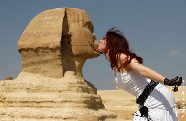 A tourist poses for a picture with the Sphinx at the Pyramids of Giza in Cairo, Egypt, on October 19, 2011
