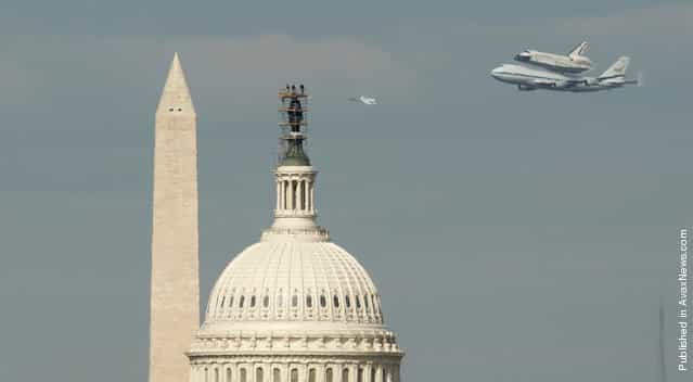 Spectators atop the U.S. Capitol Building watch as Discovery and a a NASA T-38 aircraft fly past the Washington Monument, on April 17, 2012