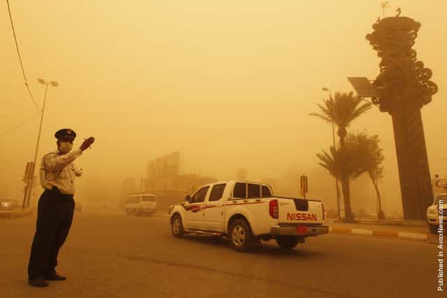 A traffic policeman directs vehicles during a sandstorm in Baghdad's Karrada district April 19, 2012