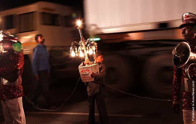 A young Indian boy holds a moving light as bandmasters wait for a wedding procession to start near Bijnor, Uttar Pradesh, India, April 18, 2012. The barat, a wedding procession with lights and music, is a very important part of countryside wedding celebrations