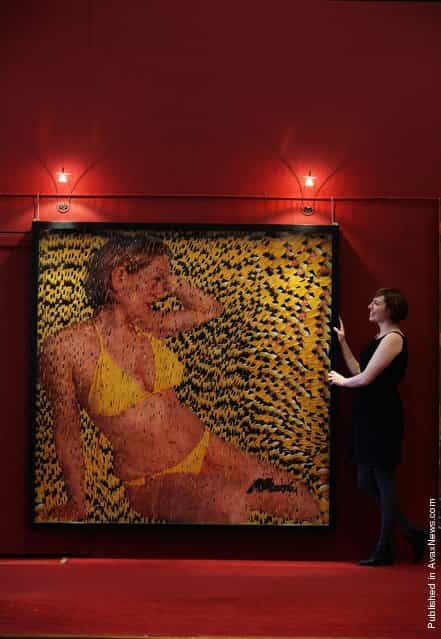 Charlotte Roirdan, from Lyon and Turnbull, poses near portrait of a woman wearing a bikini made entirely out of postcards of the Queen
