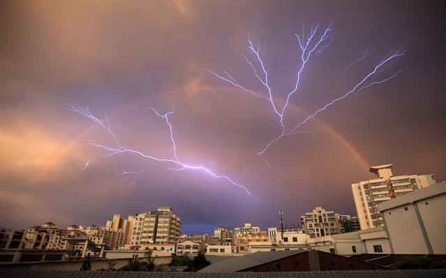 A rainbow is seen in the sky as lightning strikes after a rainstorm in Haikou, Hainan province, China, on May 13, 2012
