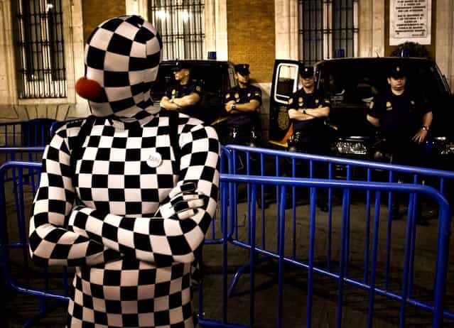 A demonstrator dressed in a chess board costume performs next to police officers during a protest at Puerta del Sol plaza in Madrid