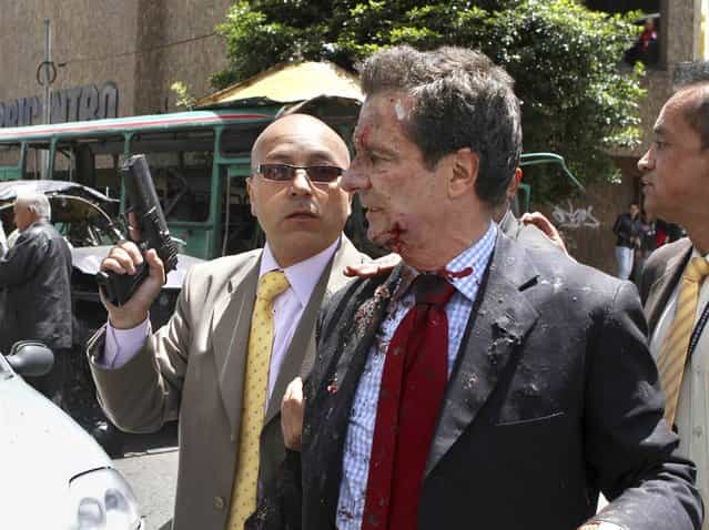 Former Colombian Interior Minister Fernando Londono is accompanied by a bodyguard after being injured in an explosion in a central avenue in Bogota on May 15, 2012