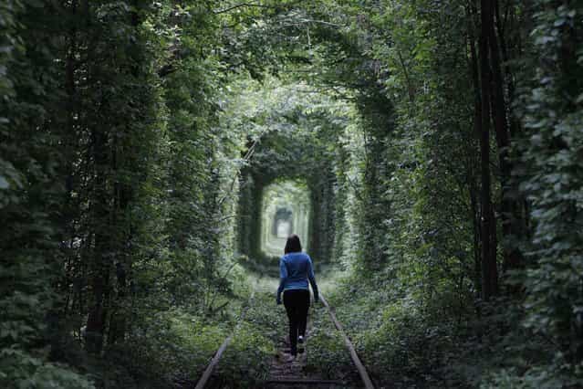 A girl walks on a disused railway track, through what is known locally as the [Tunnel of Love], in small town Kleven some 350 km (217 miles) off western Kiev May 13, 2012