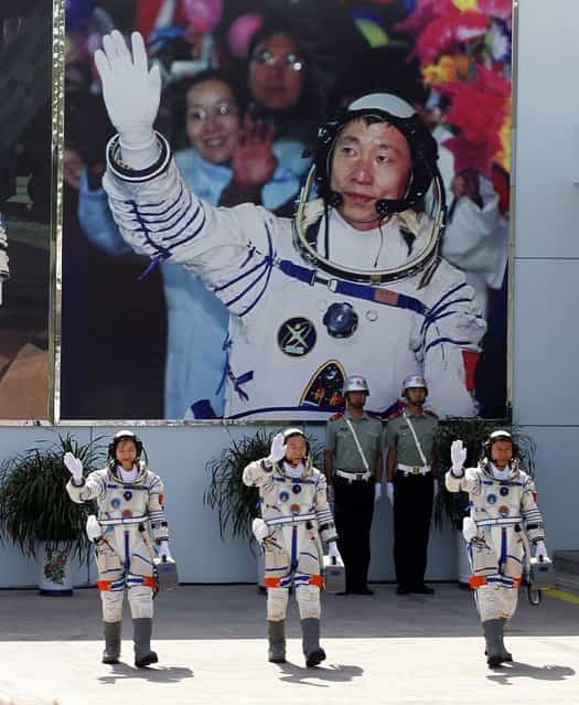 Chinas astronauts from left., Liu Yang, Jing Haipeng and Liu Wang wave and walk before a giant portrait of Chinas first astronaut Yang Liwei, as they depart for the Shenzhou 9 spacecraft rocket launch pad at the Jiuquan Satellite Launch Center in Jiuquan, China, Saturday, June 16, 2012