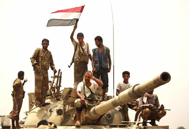 Yemeni army soldiers and tribesmen wave a flag as they drive through Zinjibar, Yemen, after retaking the city from al-Qaida militants on June 14, 2012
