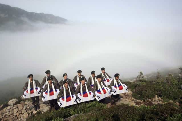Soldiers pay a silent tribute after completing the exhumation of the remains of South Korean soldiers, who are believed to have been killed by North Korean soldiers during the 1950-53 Korean War at an excavation site on a mountain in Sokcho June 14, 2012