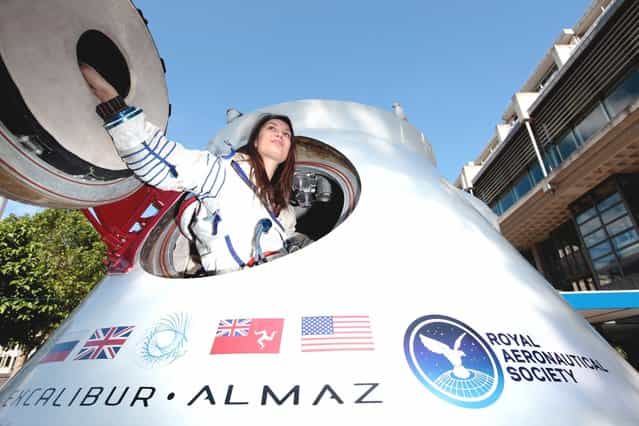 Jenn Sander from Red Robin PR, wearing a spacesuit once worn by US Astronaut Peggy Whitson, sits inside a re-entry capsule owned by Excalibur Almaz