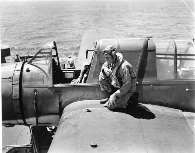 Back from mission over Guam (6-16-1944). Airdale Anderson laughs. near his hand note Jap shrapnel hole, which went through gas tank