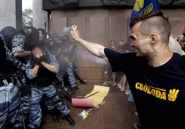 Opposition protesters spray tear gas against riot police in front of the Ukrainian House in central Kiev, Ukraine