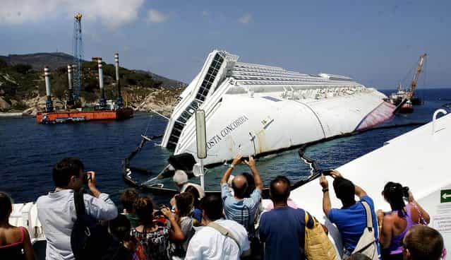 Tourists take photographs of the Costa Concordia wreckage as they arrive on a ferry to Giglio Island, Italy