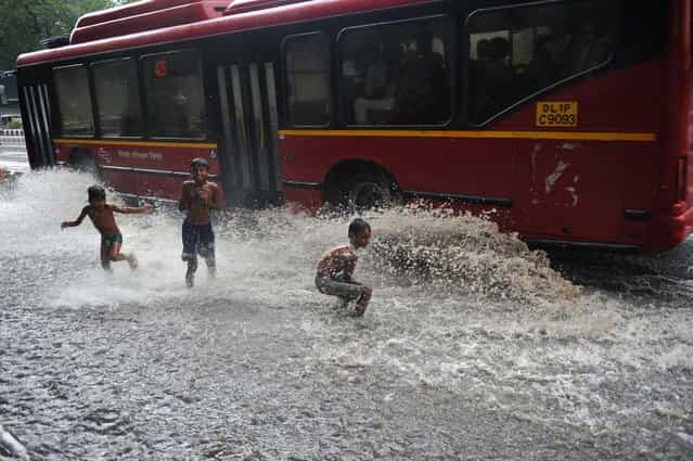 Indian children play in a water-logged street after a spell of monsoon rain in New Delhi on July 12, 2012