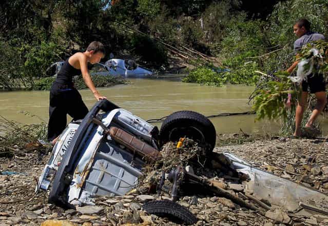 Children view a car partially buried in mud on the bank of the river after flooding in the town of Nizhnebakansky on July 9, 2012