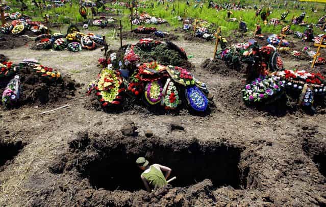A soldier digs a grave for those who died during floods in Krymsk, Russia on July 10, 2012