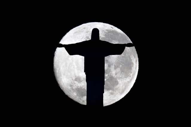 A full moon rises behind the Christ the Redeemer statue in Rio de Janeiro, Brazil on July 4, 2012