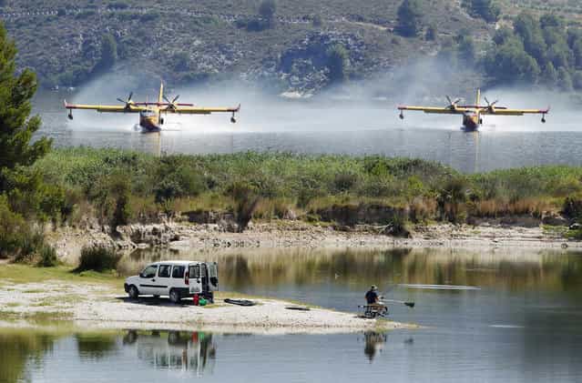 Firefighting planes fetch water from the Beniares reservoir to fight a wildfire next to the Sierra Mariola Nature Park in Cocentaina near Alicante, July 13, 2012