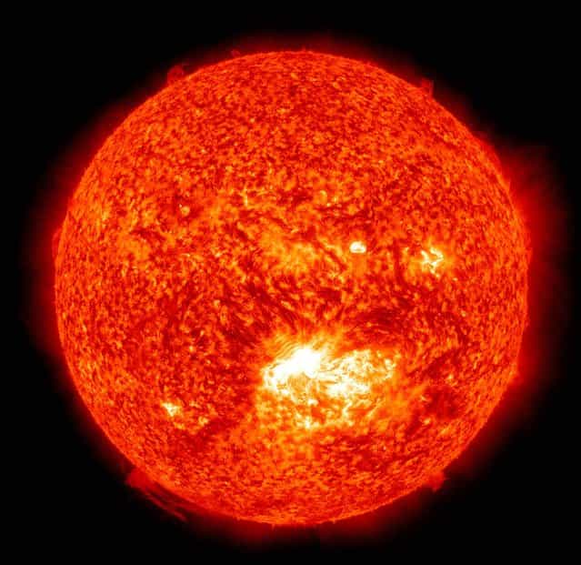 The 304 Angstrom wavelength, which is typically colorized in red shows a solar flare, lower center, erupting from the sun