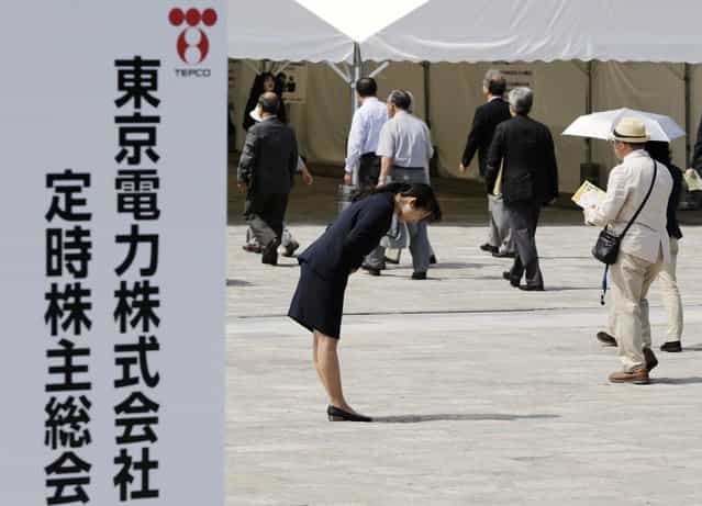 A Tokyo Electric Power Co (TEPCO) employee bows deeply as shareholders enter the venue of the company's annual general shareholders meeting in Tokyo on July 1, 2012