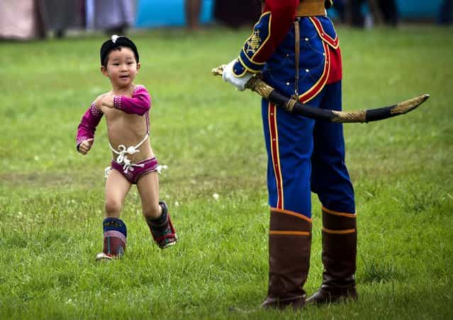 A boy in costume runs past a member of the honor guard during the Naadam Festival in Ulan Bator on July 11, 2012