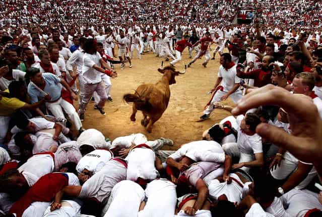 A cow jumps over revelers in a bullring during the second running of the bulls at the San Fermin fiestas in Pamplona, Spain on July 8, 2012