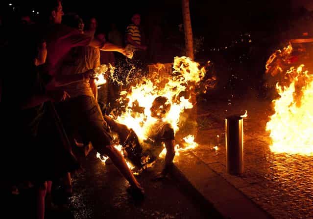 People try to extinguish flames after a man set himself on fire during a protest in Tel Aviv on July 14, 2012