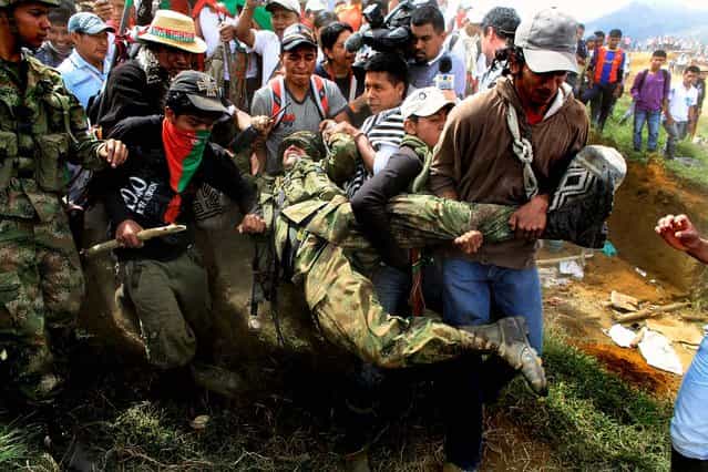 Nasa Indians drag off a soldier in Toribio, southern Colombia on July 17, 2012. Leaders of the 115,000 Nasa people are demanding government troops and leftist rebels alike go away and leave them in peace. (Photo by William Fernando Martinez/Associated Press)