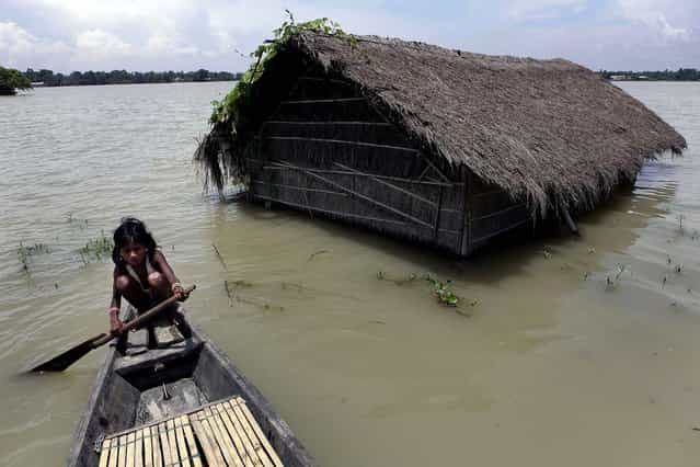 A girl rows a boat near her submerged house in Burhaburhi village, India on July 20, 2012. Days of continuous rainfall has raised the water level of the Brahmaputra River and its tributaries and flooded the area. (Anupam Nath/Associated Press)