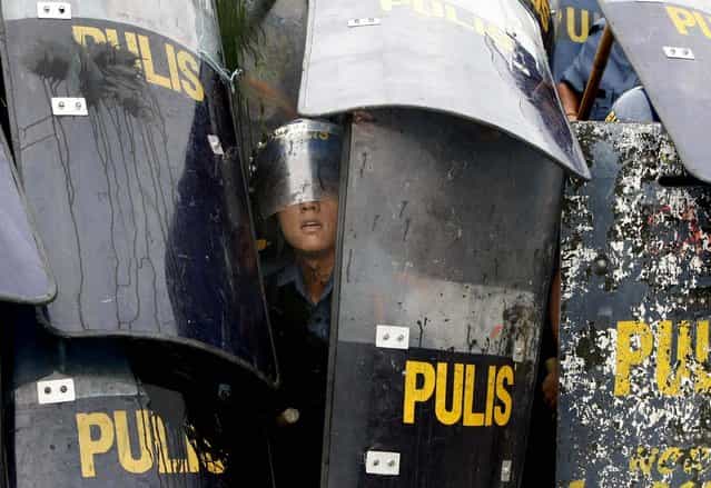 Police regroup themselves following a clash with protesters as the latter try to get closer to the Philippine Congress to protest the third State of the Nation address of Philippine President Benigno Aquino III, in suburban Quezon city, northeast of Manila on July 23, 2012. (Photo by Bullit Marquez/Associated Press)