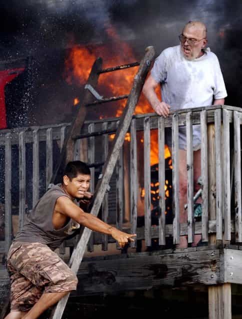 Edwardo Martinez yells for help as he tries to rescue Pete Lui off the balcony of Lui's home in Racine, Wisconsin, as flames spread through the second floor apartment on July 24, 2012. (Photo by Gregory Shaver/Journal Times)