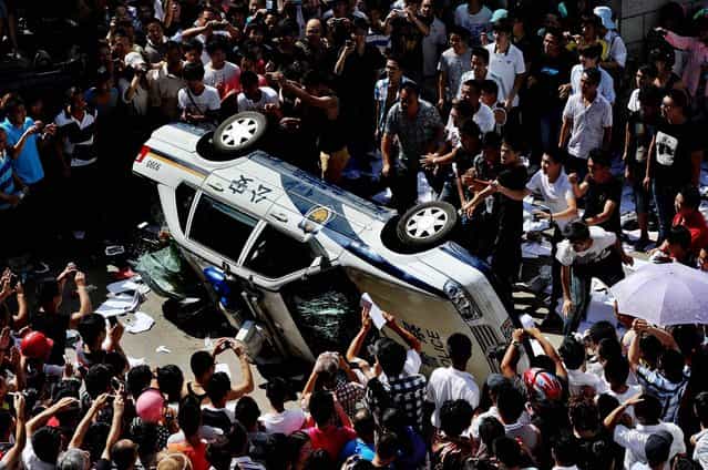 Protesters push over a police vehicle as they gather to demonstrate against plans for a water discharge project in Qidong, China on July 28, 2012. The government in the city announced on its official website Saturday that the plans were scrapped amid the strong opposition by local residents, who are concerned over potential pollution. (Photo by Kyodo News)