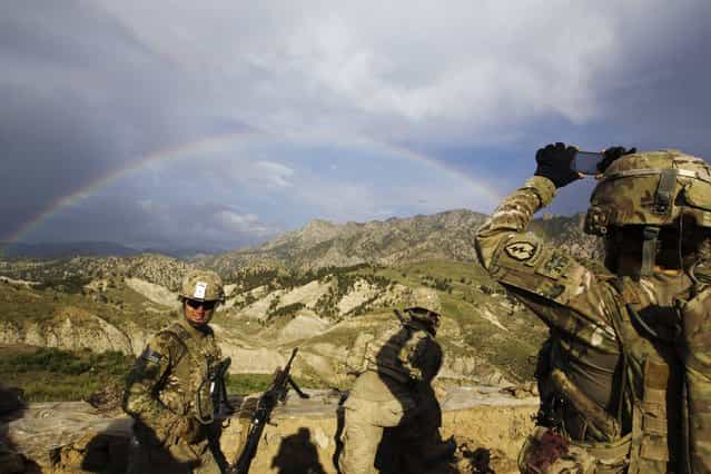 A paratrooper from Chosen Company of the 3rd Battalion (Airborne), 509th Infantry photographs a rainbow towards the end of a helicopter assault mission to improve their biological database, near the town of Ahmad Khel in Afghanistan's Paktiya Province July 16, 2012. Picture taken July 16, 2012. (Photo by Lucas Jackson/Reuters)