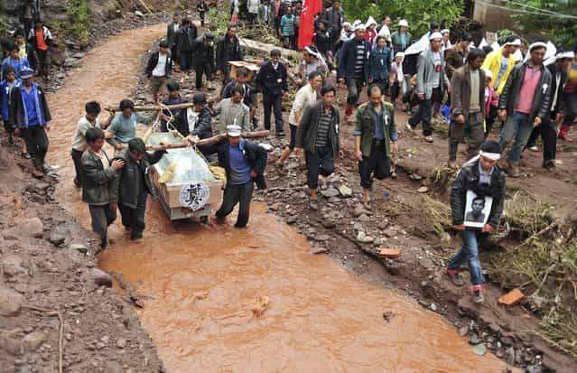 Villagers carry the coffin and portrait of a victim who was killed by a flash flood as they wade through a stream during a funeral in Sujia village of Zhaotong, Yunnan province July 17, 2012. The flood caused by heavy rain falls in Sujia Village of Zhaotong since Sunday, left 2 dead and 8 injured. Torrential rain last week affected more than 2 million people in several southern Chinese provinces, according to local authorities, Xinhua News Agency reported. (Photo by Wong Campion/Reuters Photo)