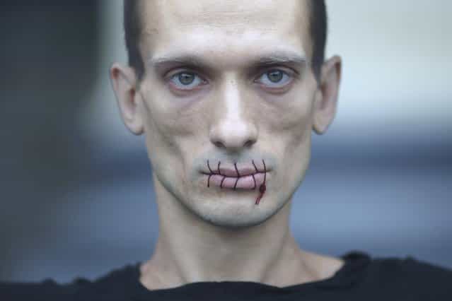 Artist Pyotr Pavlensky, a supporter of jailed members of russian female punk band [Pussy Riot], looks on with his mouth sewed up as he protests outside the Kazan Cathedral in St. Petersburg, Russia, July 23, 2012. A court on Monday rejected a request to call President Vladimir Putin and the head of the Russian Orthodox Church to testify in the trial of three female punk rockers who derided Putin in a protest in the country's main cathedral, their lawyer said. Picture taken July 23, 2012. (Photo by Trend Photo Agency/Handout/Reuters)