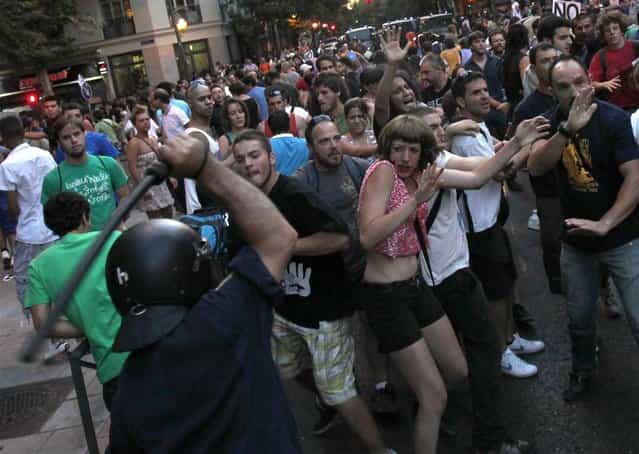 A riot policeman hits demonstrators outside the Spanish socialist PSOE party headquarters in Madrid on July 14, 2012. (Photo by Juan Medina/Reuters)