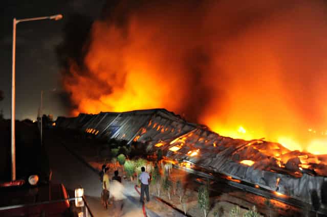 Indian firefighters try to control the blaze at the Hitachi Airconditioner Manufacturing facility at Karan Nagar near Kadi town, some 50 kms from Ahmedabad, early on July 19, 2012. The cause of the overnight fire, which gutted the plant that manufactures some 350,000 air conditioning units per year, is still unknown. Hundreds of contractual workers employed at the plant have been on strike since June 8, alleging exploitation and low wages. (Photo by Sam Panthaky/AFP)