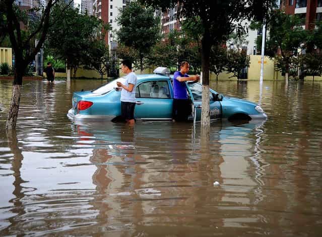 A taxi driver and his passenger get stuck in the floodwaters in Tianjin, China on July 26, 2012. (Photo by Associated Press)