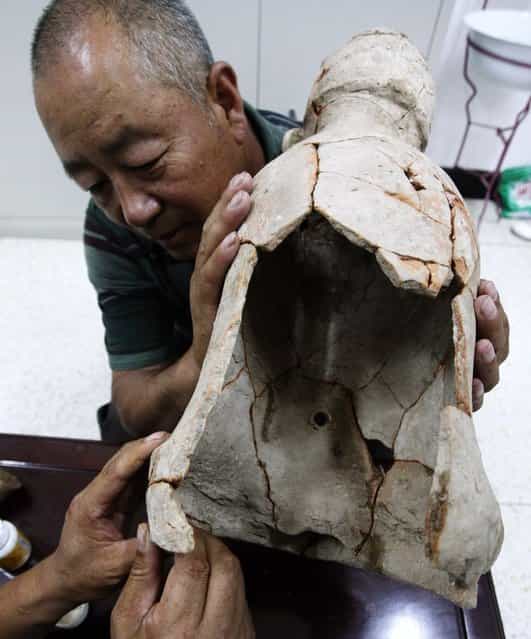 Archaeologists repair a pottery statue found in Aohan Banner, a county-level administrative region in North Chinas Inner Mongolia autonomous region, July 3, 2012. The statue, which is 55-centemeters tall, dates back to about 5,300 years ago. (Photo by Xinhua)