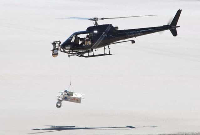 This test for the radar system to be used during the August 2012 descent and landing of NASA Mars rover Curiosity mounted an engineering test model of the radar system onto the nose of a helicopter. During the final stage of descent, NASAs Mars Science Laboratory mission will use a [sky crane] maneuver to lower Curiosity on a bridle from the missions rocket-powered descent stage. The descent stage will carry Curiositys flight radar. This test on May 12, 2010, at NASA Dryden Flight Research Center, in Edwards, California, included lowering a rover mockup on a tether from the helicopter to assess how the sky crane maneuver will affect descent-speed determinations by the radar. (Photo by NASA)